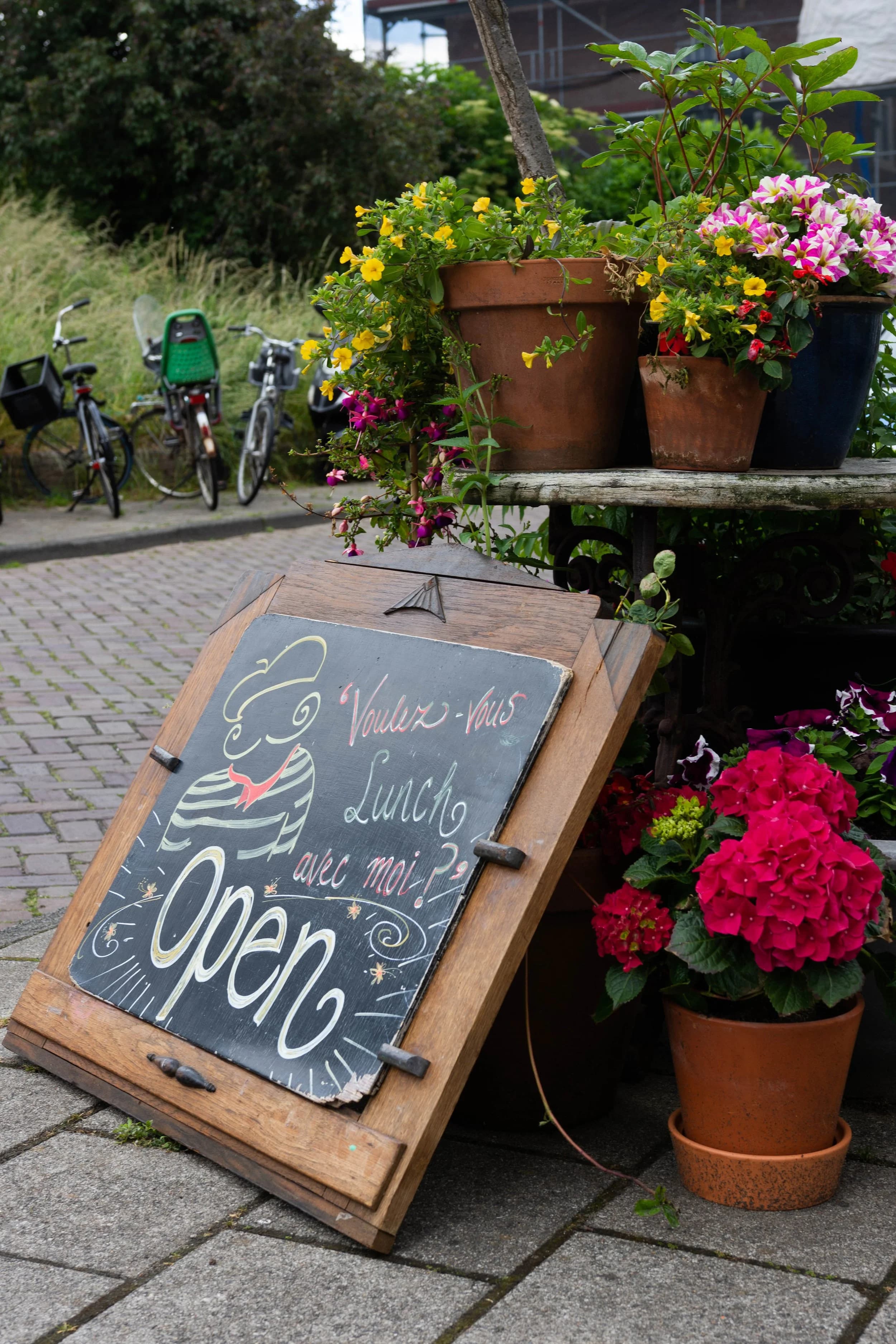 Zwart schoolbord met getekende chef-kok en bloemen buiten